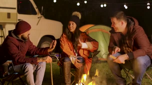 Groupe d'amis proches se détendre ensemble autour du feu de camp dans une nuit froide d'automne — Video