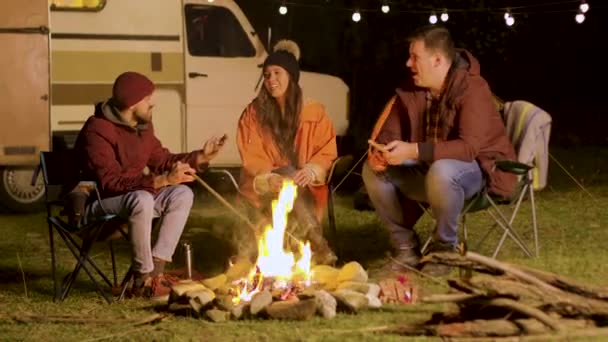 Bearded man telling a funny joke to his friends around camp fire — Stock Video