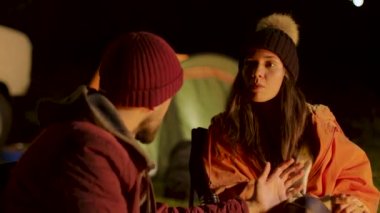 Dağlarda soğuk bir gecede kamp ateşi etrafında yakın arkadaşlar.