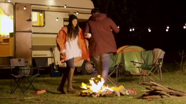 Jovem casal alegre dançando ao redor fogo acampamento na noite fria do outono — Vídeo de Stock