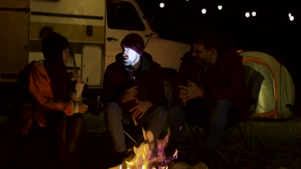 A szakállas férfi ijesztő történetet mesél a barátainak a tábortűz körül. — Stock videók