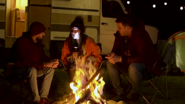 Girl telling her friends a scary story to her friends around camp fire — Stock Video