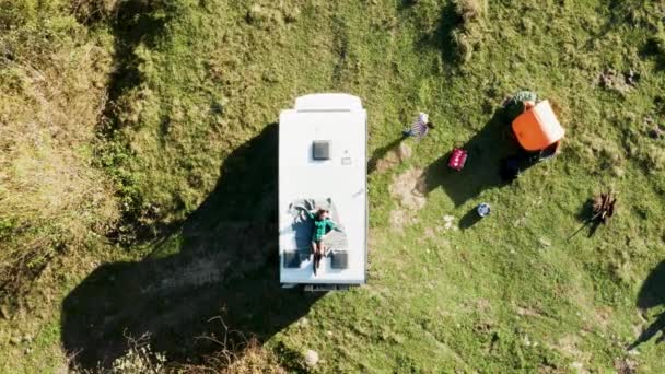 Vue du dessus de la belle jeune femme relaxant sur le dessus du camping-car rétro — Video