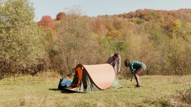 Mooi jong stel dat elkaar helpt bij het opzetten van de campingtent — Stockvideo