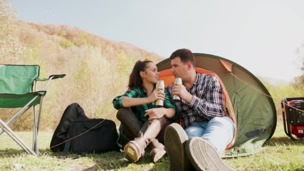 Casal desfrutando de uma bebida juntos na frente de sua barraca de acampamento — Vídeo de Stock