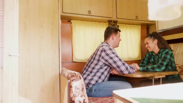 Pareja riendo juntos y tomados de la mano dentro de retro autocaravana — Vídeo de stock