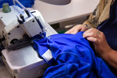 Dikiş makinesinde çalışan bir kadına ellerinle yaklaş.