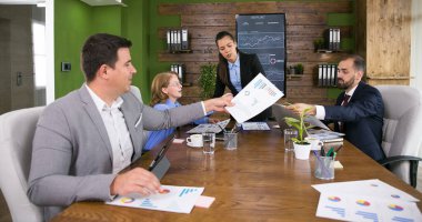 İş adamları birlikte çalışıyor ve toplantı odasında bilgi alışverişinde bulunuyorlar.