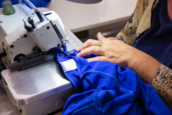 Cerrar con las manos en una costurera que trabaja en una máquina de coser — Foto de Stock
