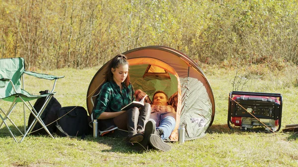 男朋友躺在帐篷上，女朋友在看书 — 图库照片