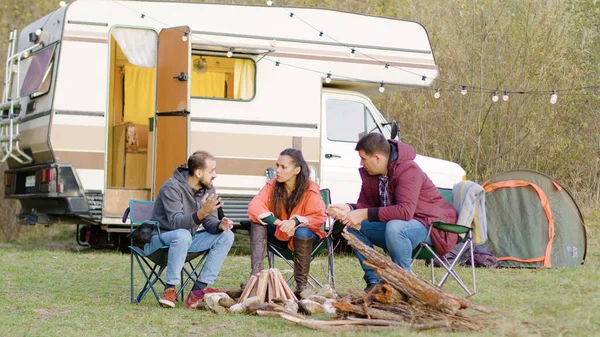 Hombre contando una historia a sus amigos sentados en sillas de camping — Foto de Stock