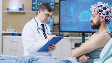 Beyin araştırmalarında doktor hasta yatağının yanında kalıyor ve not alıyor.