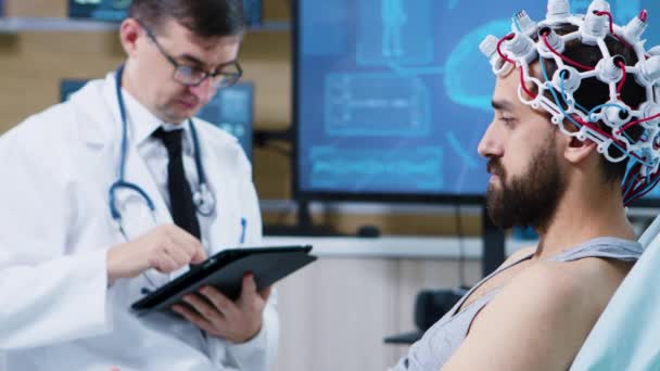 A beteg kórházi ágyon ül és agyhullámokat visel szkennelés headset — Stock videók