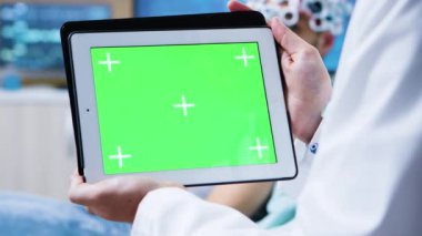 Doktor beyin araştırması için klinikte yeşil ekranlı tablet tutuyor.