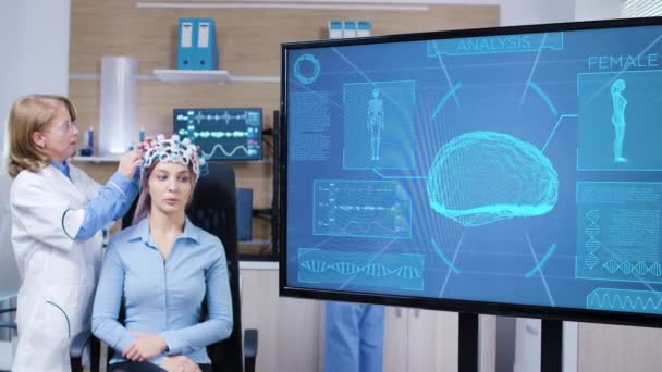 Pantalla de televisión con actividad cerebral de mujeres que usan escáner cerebral — Vídeos de Stock