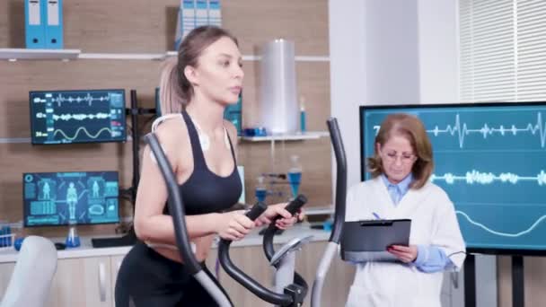 Female doctor mesuring the heart activity of female athlete — Stock Video