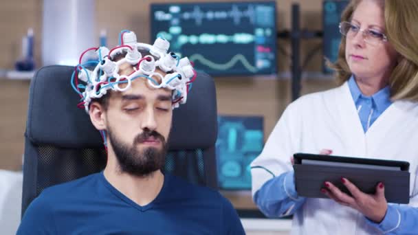 Männlicher Patient mit geschlossenen Augen, während Arzt Gehirnaktivität überprüft — Stockvideo