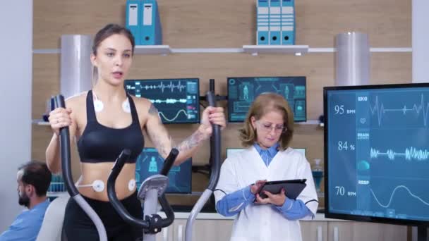 Женщина-ученый следит за сердечной активностью спортсменки — стоковое видео