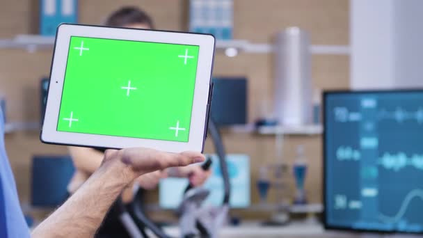 Dolly shot of doctor in sport science holding tablet with green screen — Stock Video