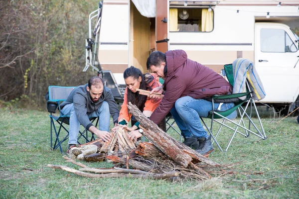 Hipster amigos haciendo juntos un fuego de campamento en el bosque de montaña —  Fotos de Stock