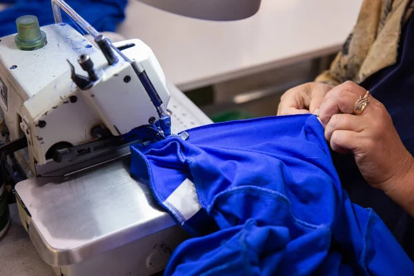 Cerrar con las manos sobre una mujer cosiendo algo en la máquina de coser — Foto de Stock