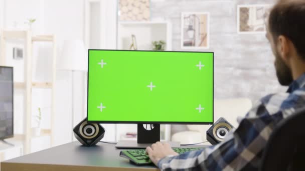 Man werkt op groen scherm Pc display, over de schouder schot — Stockvideo