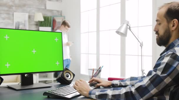 Людина, що працює на дисплеї ПК з зеленим екраном у затишній яскравій вітальні — стокове відео