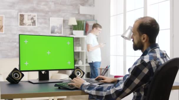 Jeune homme travaillant sur PC avec écran vert dans un salon lumineux et bien éclairé — Video