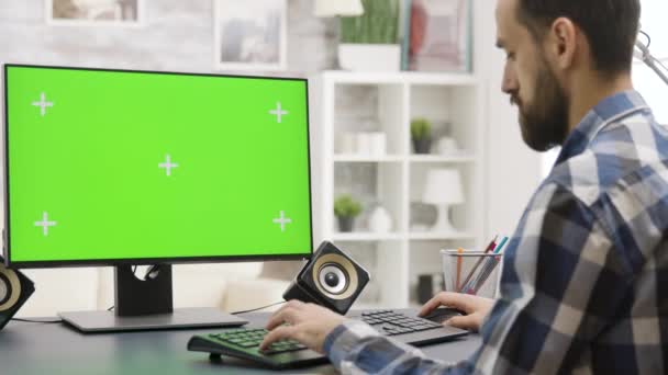 Zoom in parallax beelden van jonge man die werkt aan Pc met groen scherm — Stockvideo