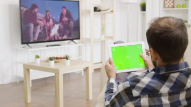 Adam televizyona bakarken yeşil ekran dijital tabletine dokunuyor