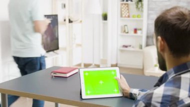 Parlak oturma odasında yeşil ekranlı dijital tablet üzerinde kayan adam