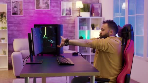 Homem barbudo sentado na cadeira de jogo alongando-se enquanto joga videogames — Vídeo de Stock