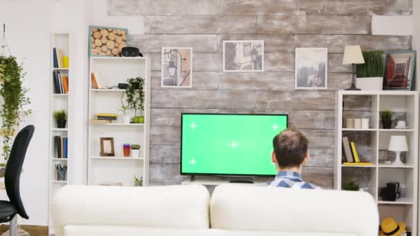 Вид на молодого человека, смотрящего спорт по телевизору — стоковое видео