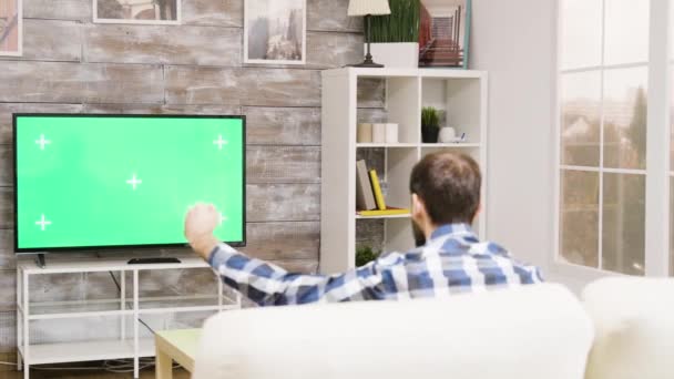 Visão traseira do jovem animando na frente da tv — Vídeo de Stock