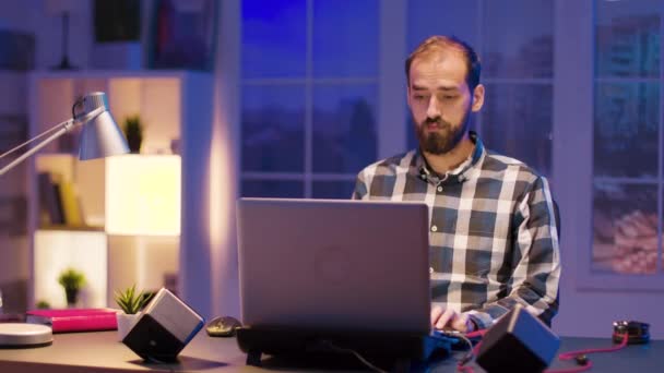 Молодой человек работает допоздна из своего домашнего офиса — стоковое видео