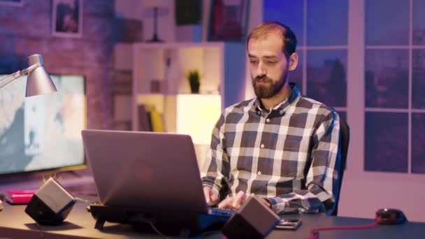 Νέος ελεύθερος επαγγελματίας εργάζεται στο laptop του από το σπίτι — Αρχείο Βίντεο