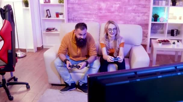 Vrolijk paar zitten op hun bank en het spelen van online games — Stockvideo