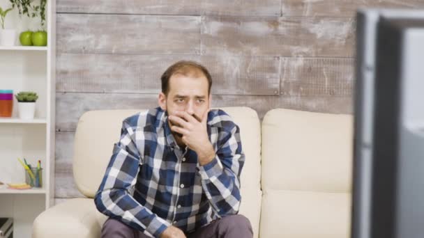 Bearded man sitting on sofa with shocked expression — Stock Video