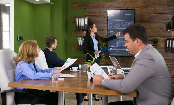 Geschäftsmann im Anzug hört ihrem Kollegen bei der Präsentation von Charts auf dem Fernsehschirm zu — Stockfoto