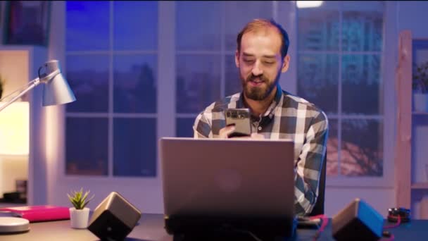 Joven freelancer escribiendo en su teléfono mientras hace una videollamada — Vídeo de stock