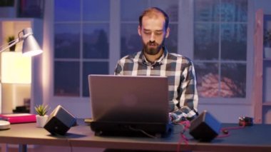 Çok çalışan bir adam laptopuyla evden geç saatlere kadar çalışıyor.