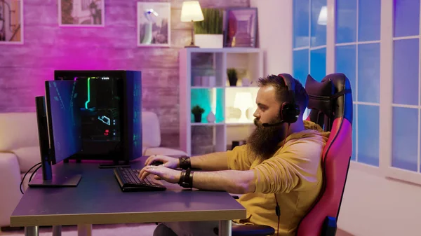 Barbudo hombre jugando videojuegos en una habitación con coloridos neones — Foto de Stock