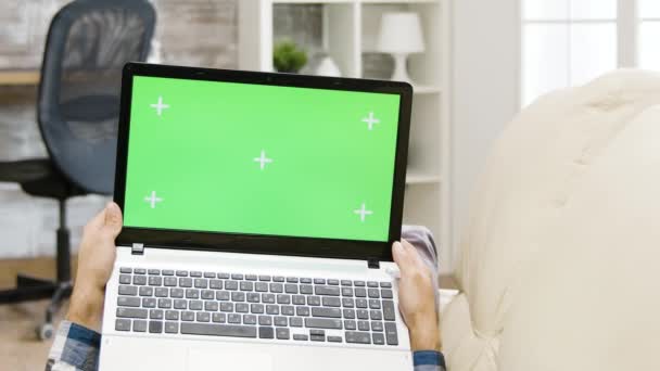 Zoom fora paralaxe tiro de homem segurando um laptop tela verde — Vídeo de Stock
