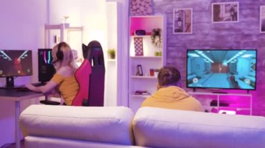Renkli ışıkları olan bir odada online video oyunu oynayan çift