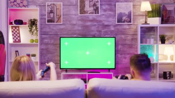 Молода пара використовує бездротові контролери, щоб грати в онлайн ігри — стокове відео