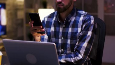 Genç işadamı cep telefonuna bakarken gülümsüyor.