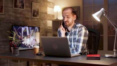 Girişimci dizüstü bilgisayarla çalışırken cep telefonuyla konuşuyor