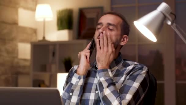 Уставший бизнесмен зевает во время телефонного разговора — стоковое видео