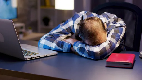 仕事の多い起業家は自宅のオフィスで横になって机の上で寝ています — ストック写真