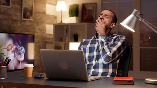 Gerente cansado bostezando mientras trabaja en el ordenador portátil —  Fotos de Stock